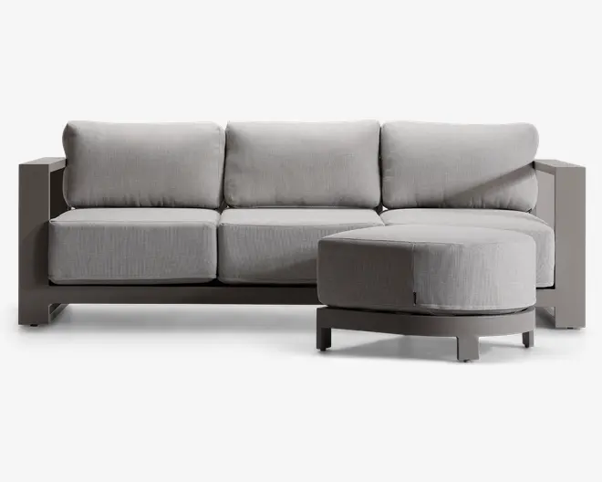 Moderne hjørnesektion med højrevendt chaiselong. Sofaen har tykke, lysegrå hynder med let tekstur, understøttet af en solid, kantet ramme i en matchende neutral farve. Designet har brede armlæn og lav ryg, hvilket giver et moderne og komfortabelt udtryk.