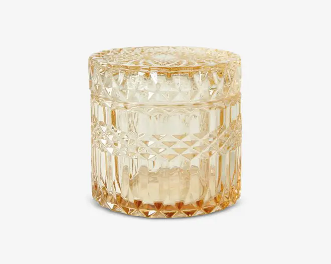 Rund glasbeholder med tilhørende låg, dekoreret med et tekstureret, diamantmønstret design på sider og top. Glasset har en varm ravfarvet tone, hvilket giver det et vintage eller elegant udseende. Beholderen er robust og dekorativ, velegnet til opbevaring af småting eller som pyntegenstand.