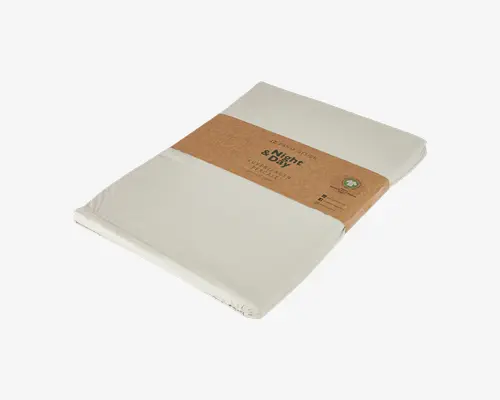 Et pænt sammenfoldet, cremefarvet tekstilprodukt indpakket i et brunt papirbånd. Båndet har miljøvenlige symboler og produktinformation, hvilket antyder bæredygtigt eller økologisk materiale. Stoffet ser glat og blødt ud med rene, færdige kanter, hvilket indikerer høj kvalitet.