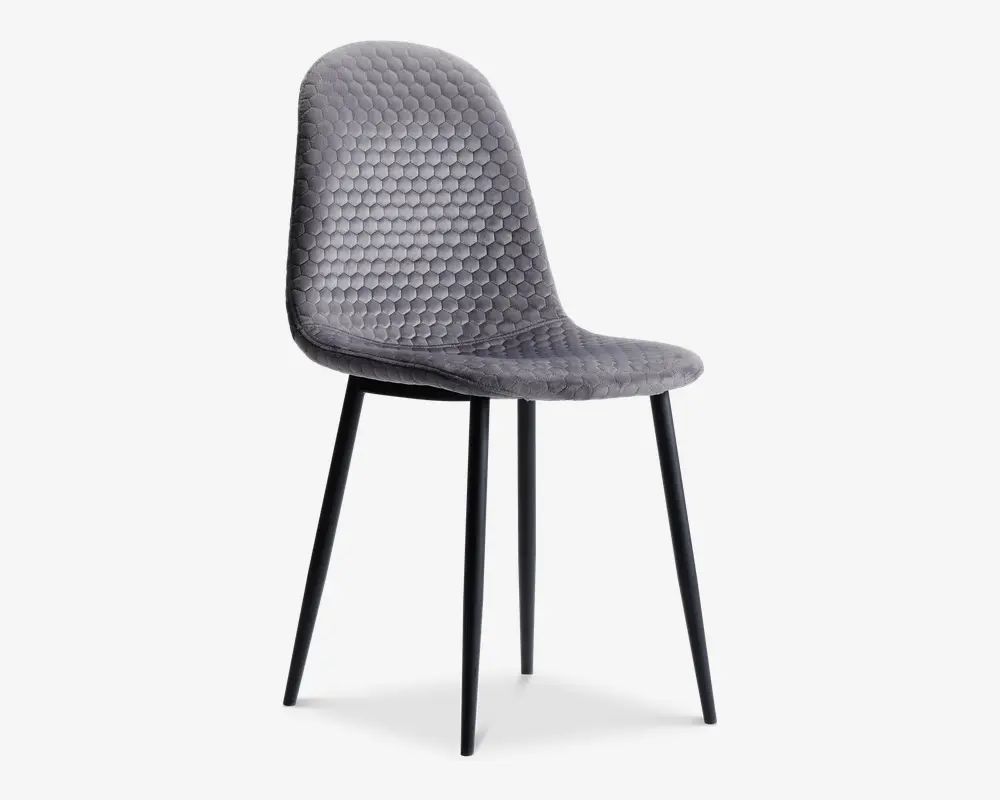 Stol med buet ryglæn og sæde polstret i gråt stof med et bikubeformet quiltet mønster. Stolen har slanke, sorte metalben, der er let skråtstillede for stabilitet. Designet er moderne og minimalistisk med et blødt, polstret sæde for ekstra komfort.