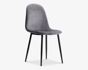 Stol med buet ryglæn og sæde polstret i gråt stof med et bikubeformet quiltet mønster. Stolen har slanke, sorte metalben, der er let skråtstillede for stabilitet. Designet er moderne og minimalistisk med et blødt, polstret sæde for ekstra komfort.