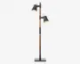 Høj gulvlampe med rektangulær sort fod og en stang i træ. Lampen har to justerbare lampeskærme i sort metal, som sidder i forskellige højder på stangen, så lyset kan rettes i forskellige retninger. Lampeskærmene er let udadbuede og har en metallisk inderside, der giver bedre lysrefleksion.