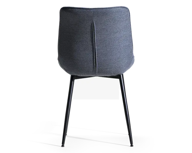 Billedet viser bagsiden af en stol med en buet, polstret ryg i mørkegråt stof. Ryggen har en lodret syning i midten som en designdetalje. Stolen har slanke, sorte metalben, der er let skråtstillede for stabilitet og et moderne udtryk.