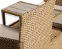 Nærbillede af et udendørsmøbel med tæt flettet syntetisk rattan i en naturlig beige farve. Armlænet har et integreret sidebord med en lys, lamelagt overflade. Sædet har en tyk, lys beige hynde for ekstra komfort. Konstruktionen virker solid og vejrbestandig, velegnet til terrasse eller have.