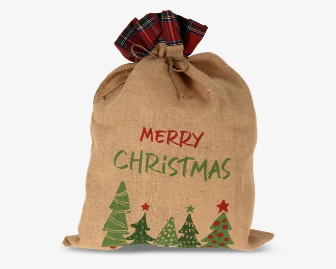 En gavepose af jute med snørelukning, hvor toppen er dekoreret med rød og grøn ternet stof. Forsiden af posen har teksten 'Merry Christmas' i rød og grøn, samt illustrationer af forskellige stiliserede juletræer, nogle pyntet med stjerner og kugler.