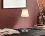 En lille bordlampe med en fod i børstet metal og en slank, lige stang. Lampen har en matteret glasskærm med et diskret marmoreret mønster, der giver et blødt og diffust lys. Designet er minimalistisk og moderne, velegnet til skriveborde eller sengeborde. Lampen er tilsluttet strøm, og ledningen er synlig fra lampens fod.
