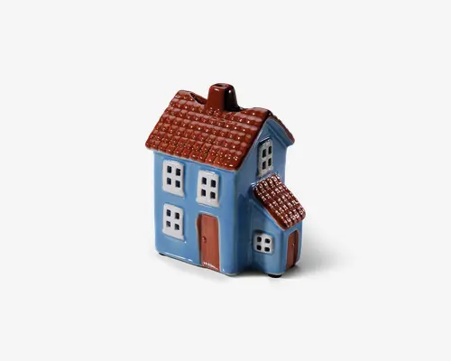 Keramisk genstand formet som et lille hus, malet blåt med brunt, tekstureret tag og brune døre. Huset har flere vinduer med hvide rammer og en lille tilbygning på den ene side, også med brunt tag. Overfladen er blank og giver et poleret udseende.