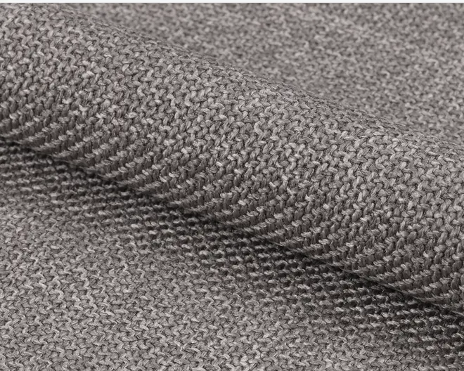 Nærbillede af et tekstureret, mellemtykt stof i en neutral grå farve. Vævningen er tæt og ensartet, med en let ru overflade, der indikerer slidstyrke. Stoffet har en mat finish og en diskret, naturlig variation i garnets tykkelse, hvilket giver et håndlavet udtryk.