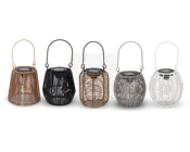 Fem dekorative lanterner med flettet rattan- eller kurveudseende, hver med hank for nem transport. Lanternerne vises i forskellige farver: naturbrun, sort, lys brun, grå og hvid. Hver lanterne har et gennemsigtigt indre rum til lyskilde og en flad top, sandsynligvis til solcellepanel eller placering af stearinlys. Designet varierer lidt i form, hvor nogle er mere runde og andre mere kegleformede.