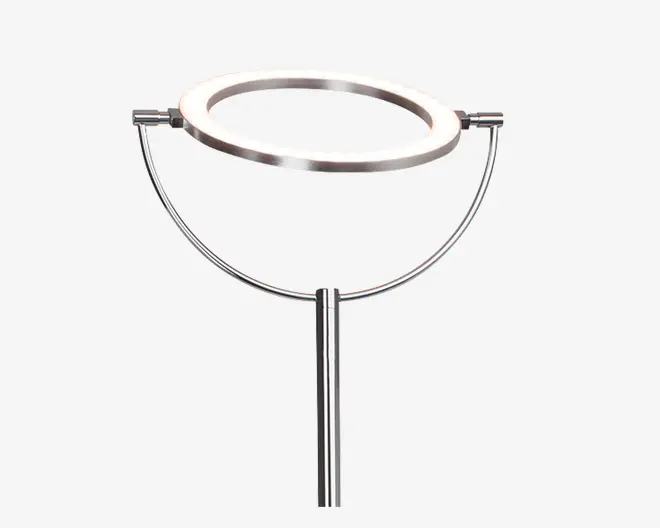 En moderne, minimalistisk lampe med en cirkulær LED-lyskrans monteret på en slank, metalramme. Lampen har en poleret kromfinish og en U-formet støtte, der holder ringen vandret over en lige, lodret stang. Designet er åbent og luftigt med rene linjer og et nutidigt udtryk.