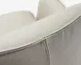 Nærbillede af en lysebeige polstret pude med glat top, strukturerede læderlignende sider og pæn lodret syning langs den buede søm.