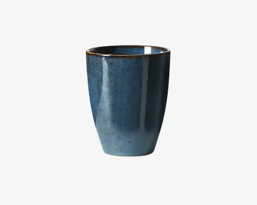 Bæger med en glat, let tilspidset cylindrisk form. Ydersiden har en blank, dybblå glasur med diskrete farvevariationer, hvilket giver et håndlavet udtryk. Kanten er markeret med en tynd, ujævn brun kant, som tilføjer et rustikt præg. Indersiden er også glaseret og matcher ydersidens blå farve.