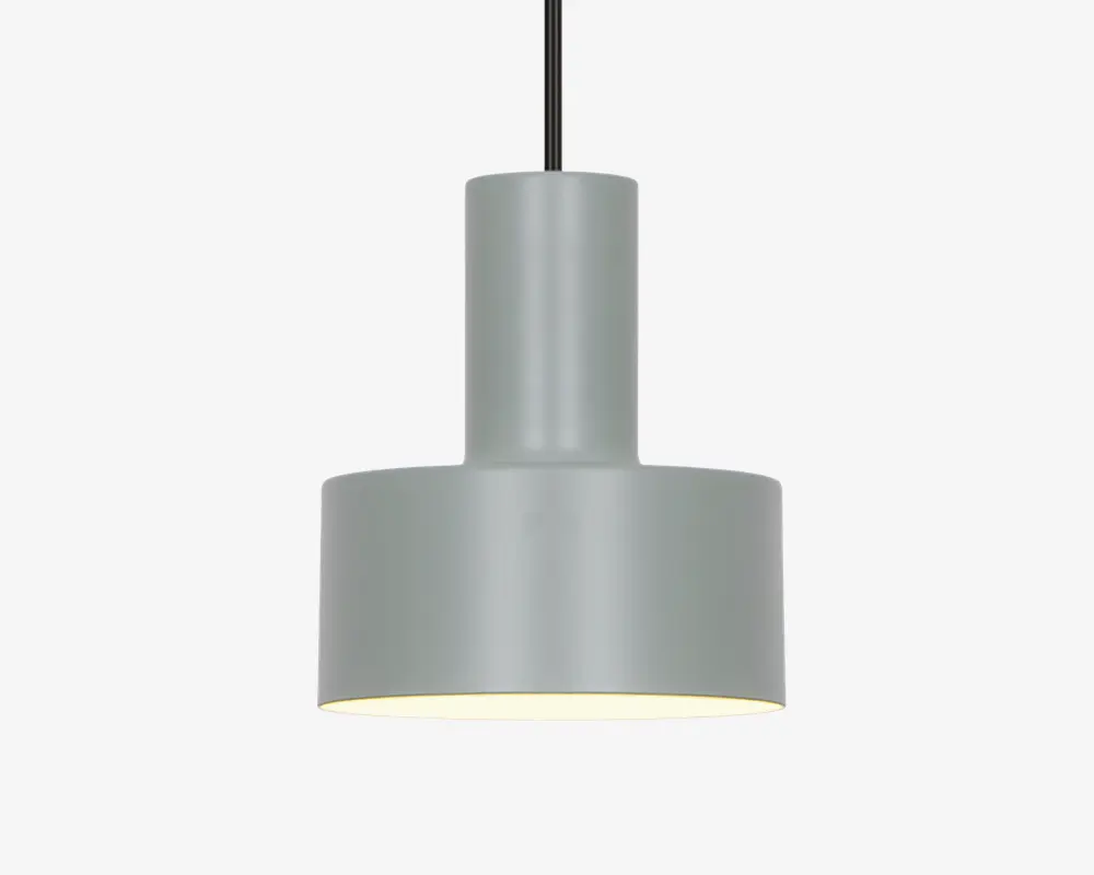 En moderne pendellampe med en matgrå cylindrisk metalskærm. Designet har en todelt struktur med en smallere cylinder øverst og en bredere cylinder nederst, hvilket giver et rent og geometrisk udtryk. Lampen hænger i en sort ledning, og indersiden af skærmen er hvid for at forbedre lysrefleksionen. Lampen giver nedadrettet lys, hvilket er ideelt til fokuseret belysning.