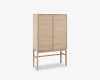 Høj skab lavet af lyst træ med to låger, der har vandrette lameldetaljer. Skabet står på fire slanke ben, som er forbundet med støttebøjler, hvilket giver et løftet og let udtryk. Designet er minimalistisk og moderne med rene linjer og en naturlig træfinish.