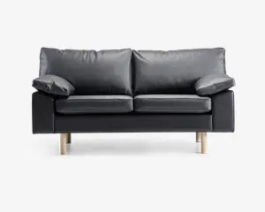 En moderne to-personers sofa betrukket med glat sort læder og udstyret med bløde, aftagelige ryg- og sædehynder. Sofaen har brede, polstrede armlæn og står på fire lyse træben, hvilket giver et nutidigt udtryk. Designet er minimalistisk, og materialerne tyder på nem vedligeholdelse og god komfort.