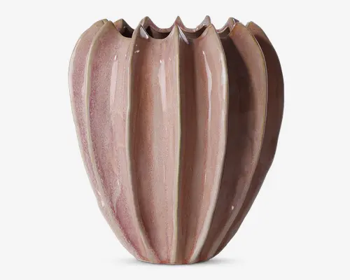 En dekorativ vase med et unikt rillet design, der har lodrette riller, som skaber en skulpturel og organisk form. Vasen har en blank overflade i en blød, afdæmpet rosa farve med diskrete nuancer. Den øverste kant er bølget og ujævn, hvilket giver et kunstnerisk udtryk.