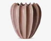 En dekorativ vase med et unikt rillet design, der har lodrette riller, som skaber en skulpturel og organisk form. Vasen har en blank overflade i en blød, afdæmpet rosa farve med diskrete nuancer. Den øverste kant er bølget og ujævn, hvilket giver et kunstnerisk udtryk.