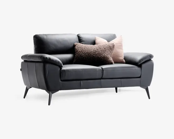 En moderne 2-personers sofa betrukket med glat sort læder og bløde, polstrede armlæn og sædehynder. Sofaen har slanke, skrå metalben, der giver et moderne udtryk. Den er pyntet med tre dekorative puder: én i et tekstureret, fluffy brunt stof og to i et blødt, lysebeige materiale, hvilket tilføjer både komfort og stil.