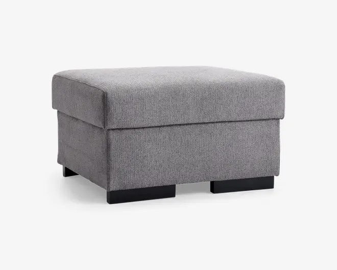 Firkantet puf med en blød, polstret top og betrukket med lysegråt stof. Puffen har rene, moderne linjer og står på korte, solide sorte ben. Stoffet har en diskret vævet struktur, og det samlede design er minimalistisk, hvilket gør den velegnet til moderne indretninger.