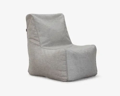 Blød loungestol i lysegrå med afslappet, sækkestolsinspireret design. Har høj ryg og bredt sæde for god komfort. Betrukket med tekstureret stof og synlige syninger langs kanterne, hvilket giver et afslappet og moderne udtryk. Stolen står direkte på gulvet uden ben eller armlæn.