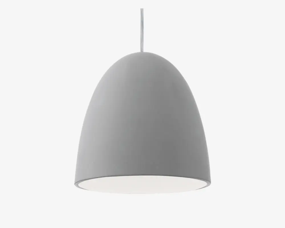 En moderne pendellampe med en glat, mat grå overflade og en enkel, kuppelformet skærm. Lampens inderside er hvid, hvilket hjælper med at reflektere lyset nedad. Lampen hænger i en enkelt ledning, hvilket giver et rent og minimalistisk udtryk.