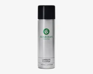 Høj, cylindrisk sølvfarvet spraydåse med sort låg. Forsiden har et grønt logo og teksten 'Guardian Furniture Care'. Nederst på dåsen står produktnavnet 'Laminate Cleaner' med fed skrift samt oversættelser på andre sprog. Designet er stilrent og moderne med en metallisk overflade.