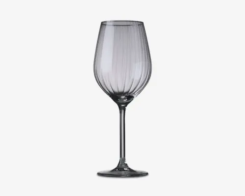 Klar glas med en høj, slank stilk og en bred, rundet skål. Skålen har lodrette, jævnt fordelte riller, som giver tekstur og et dekorativt udtryk. Glassets kant er glat og let udadbuet, hvilket fremhæver aroma og smag. Bunden er flad og cirkulær for stabilitet.