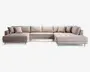 Rummelig L-formet sofa med lyse beige stofbetræk, polstrede sædehynder med knapper og fem løse ryghynder for ekstra komfort. Sofaen har to matchende pyntepuder og står på korte, skrå træben, hvilket giver et moderne og indbydende udtryk. Chaiselong-delen i begge ender giver god plads til afslapning.