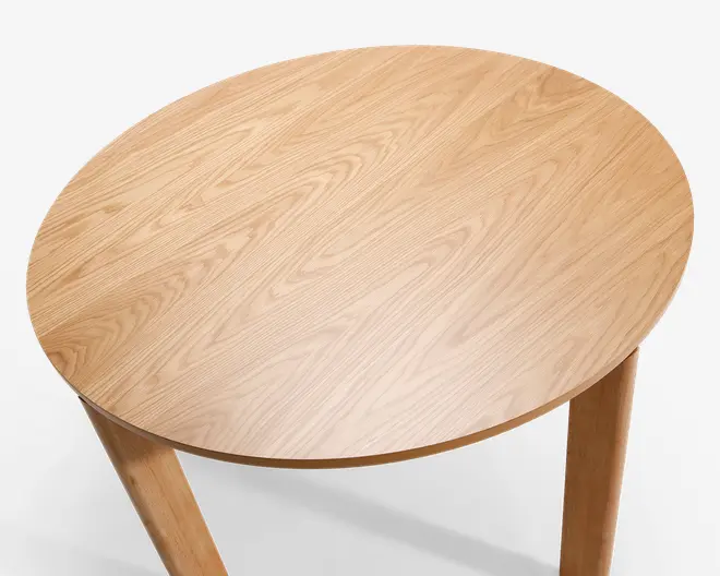 Rund bordplade med en glat, lys træfinish og synlige naturlige træårer. Overfladen er ensartet uden samlinger, og kanterne er let afrundede. Bordet understøttes af solide, lige træben, der matcher bordpladens farve og struktur.
