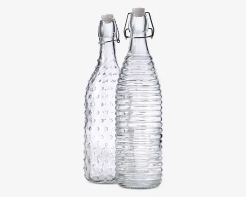 Sæt med to klare glasflasker, hver med et unikt tekstureret design. Den ene flaske har et mønster af hævede prikker, mens den anden har vandrette riller rundt om kroppen. Begge flasker er udstyret med patentpropper for sikker lukning.
