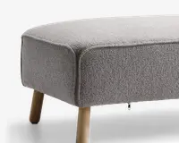 Rektangulær bænk med lysegråt tekstureret stofbetræk og afrundede kanter. Bænken står på skråtstillede ben af lyst træ. Designet er minimalistisk og moderne med synlige syninger langs kanterne.