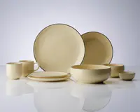 Et sæt cremefarvet keramikservice med blank overflade og en diskret mørk kant langs kanterne. Sættet indeholder store og små tallerkener, skåle i forskellige størrelser samt krus med behagelige hanke. Designet er minimalistisk og moderne med bløde, afrundede former og ensartet farve.