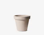 En enkel, rund urtepotte med en glat, mat overflade i en lys beige farve. Potten har en bred kant øverst for nem håndtering og en let tilspidset form mod bunden. Den virker robust og egnet til både indendørs og udendørs brug.