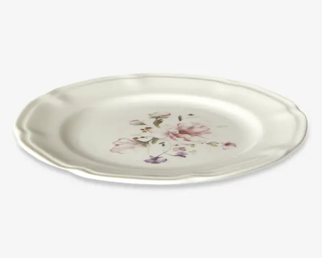 Rund keramiktallerken med let bølget kant og en glat, blank overflade. Midten har et fint blomsterdesign i bløde rosa, lilla og grønne nuancer, hvilket giver tallerkenen et elegant og vintage udtryk.