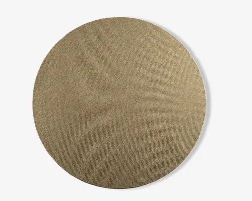 Rund, flad genstand med en tekstureret, vævet overflade i en neutral beige farve. Kanterne er glatte og jævne, og materialet ligner stof eller en tekstilblanding, hvilket giver et naturligt og let groft udseende.