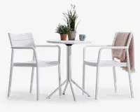 Et moderne udendørs cafésæt bestående af to hvide stole med armlæn og lamel-ryg samt et rundt hvidt bord med firebenet søjlebase. Bordet er pyntet med to potteplanter og et blåt krus. Den ene stol har et lyserødt strikket tæppe hængende over ryglænet. Sættet har et rent, minimalistisk design, der passer til terrasser eller altaner.