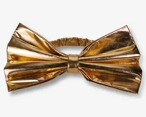 En stor, skinnende sløjfe i metallisk guld med plisseret design og en central knude. Materialet har en reflekterende, spejlblank overflade, og sløjfen er fastgjort til et elastikbånd for nem påtagning.