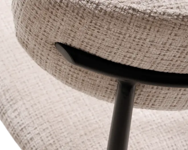 Nærbillede af en stol med polstring i lysebeige stof med en diskret ternet struktur. Ryglænet understøttes af en elegant, sort metalramme, der buer ind i sædet og fremhæver den solide konstruktion og det moderne design.