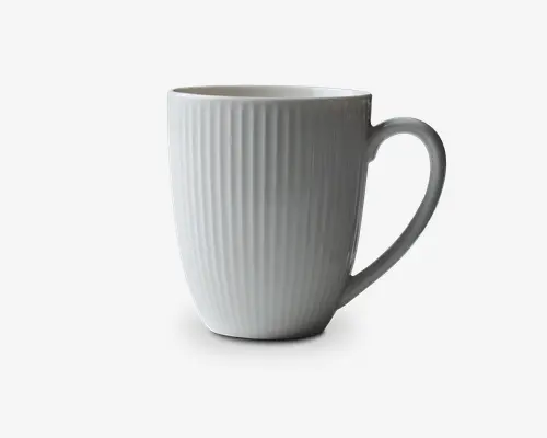 Høj, hvid keramikkop med lodrette riller over hele ydersiden. Koppen har et glat, buet håndtag og en let udadgående kant, hvilket giver et moderne og elegant udtryk.