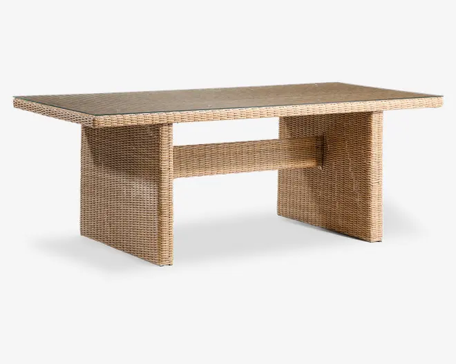 Rektangulært bord med flettet rattan-lignende finish i en naturlig lysebrun farve. Bordet har en flad, glat bordplade og to brede, solide panelben, der er forbundet med en horisontal støttebjælke. Den flettede struktur dækker hele overfladen og giver et ensartet og stilfuldt udtryk, der egner sig til både indendørs og udendørs brug.