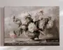 Et lærredsmaleri med en buket hvide og lyserøde pæoner arrangeret i en klassisk fodet vase. Blomsterne er malet med bløde, teksturerede penselstrøg, hvilket giver dybde og realisme. Baggrunden er i neutrale, afdæmpede nuancer, som får de sarte kronblade og grønne blade til at træde frem. Enkelte blade og kronblade ligger spredt på overfladen under vasen, hvilket giver et naturligt og afslappet udtryk til kompositionen.