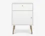 Et kompakt, moderne natbord med en ren hvid finish. Det har en enkelt skuffe øverst med en lille rund metalknop og en større skabsdør nedenunder, også med en matchende knop. Natbordet står på fire skråtstillede ben i lyst træ, hvilket giver det et udtryk i midcentury-stil. Designet er minimalistisk og funktionelt, velegnet til forskellige soveværelsesindretninger.