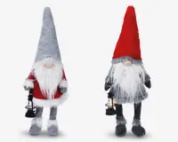 To plyssede nissefigurer med lange hvide skæg og runde næser, hver med en lille lanterne i hånden. Den venstre nisse har en høj grå hue, rød sweater med hvid kant og grå støvler. Den højre nisse har en høj rød hue, gråt tøj og matchende grå støvler. Begge har bløde, lodne teksturer og et hyggeligt, julet udtryk.