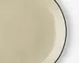 Et nærbillede af en rund, beige tallerken med en glat, blank overflade. Tallerkenen har en diskret, lidt mørkere kant og et minimalistisk design, hvilket giver den et moderne og elegant udtryk.