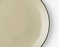 Et nærbillede af en rund, beige tallerken med en glat, blank overflade. Tallerkenen har en diskret, lidt mørkere kant og et minimalistisk design, hvilket giver den et moderne og elegant udtryk.