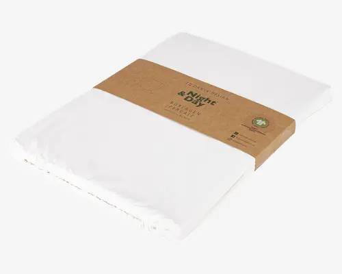 Et pænt sammenfoldet, ensfarvet hvidt tekstilprodukt indpakket i et brunt papirbånd. Båndet har trykt tekst og ikoner, der indikerer miljøvenligt materiale og dansk design. Stoffet ser glat og tæt pakket ud, hvilket antyder en frisk og ren tekstur. Emballagen er minimalistisk med tydelig branding og vigtige oplysninger på båndet.