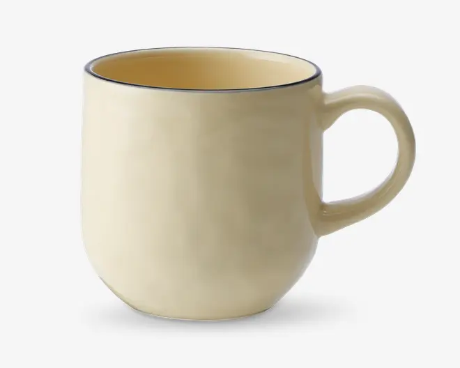 Et keramikkrus med en glat, blank overflade i en blød cremefarve. Kruset har en rundet form, et behageligt buet håndtag og en diskret mørk kant langs toppen. Indersiden er også cremefarvet og matcher ydersiden. Designet er enkelt og moderne, velegnet til daglig brug.