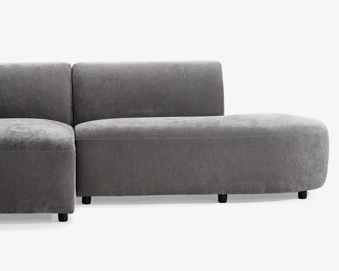 Dette møbel har et moderne, minimalistisk design med blødt, gråt stofbetræk. Sædet og ryglænet er begge tykt polstrede for ekstra komfort, og ryglænet er lige og støttende. Basen er let buet, hvilket giver et nutidigt udtryk, og møblet står på korte, solide sorte ben. Den samlede form er modulopbygget, hvilket giver fleksible muligheder for indretning i hjemmet.