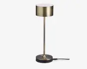 Høj, slank lampe med en cylindrisk lampeskærm i børstet guld og en matchende gylden stang. Foden er rund og flad, afsluttet i en mørk farve med en gylden detalje ved forbindelsespunktet. Lampen har et moderne, minimalistisk design og strømforsynes via en synlig ledning, der går ud fra bunden.