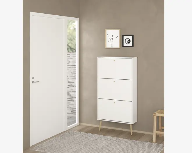 Høj, hvid opbevaringsenhed med tre frontåbnende rum, hver med en lille rund gylden knop. Enheden står på fire skråtstillede lyse træben, hvilket giver et moderne og minimalistisk udtryk. Overfladen er glat og designet er stilrent, velegnet til moderne indretning.